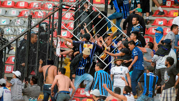 Fans clash during a Mexican soccer league match between the host Queretaro and Atlas from Guadalajara, at the Corregidora stadium, in Queretaro, Mexico, Saturday, March 5, 2022. Multiple people were injured during the brawl, including two critically. (AP Photo/Sergio Gonzalez)